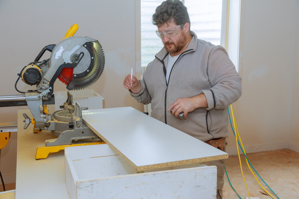 Worker cutting melamine board with a circular saw for shelves